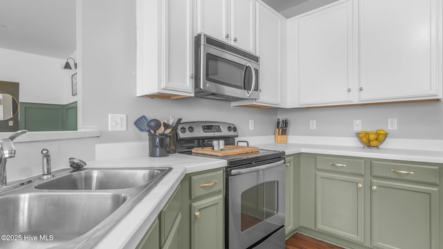 kitchen featuring sink, stainless steel appliances, green cabinetry, and white cabinets