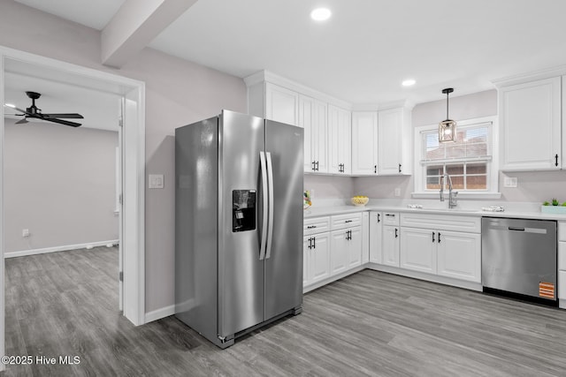 kitchen with white cabinetry, decorative light fixtures, stainless steel appliances, and light hardwood / wood-style floors