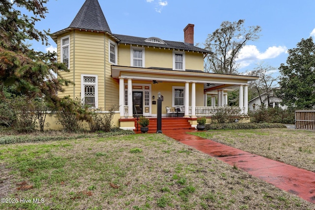 victorian home featuring a front lawn, ceiling fan, and a porch