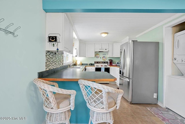 kitchen featuring light tile patterned floors, stainless steel fridge, range with electric cooktop, stacked washer and clothes dryer, and white cabinets