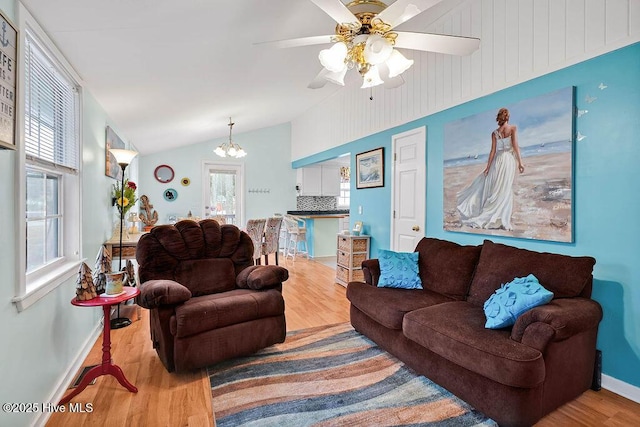 living room with lofted ceiling, hardwood / wood-style floors, ceiling fan with notable chandelier, and a healthy amount of sunlight