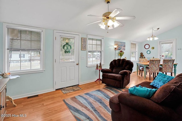 living room with lofted ceiling, ceiling fan with notable chandelier, and light wood-type flooring