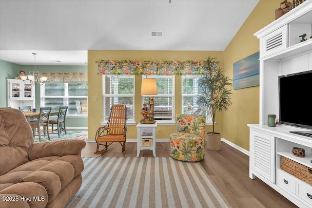 living room featuring lofted ceiling, hardwood / wood-style floors, and an inviting chandelier