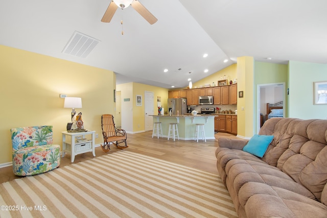 living room featuring ceiling fan, lofted ceiling, and light hardwood / wood-style floors