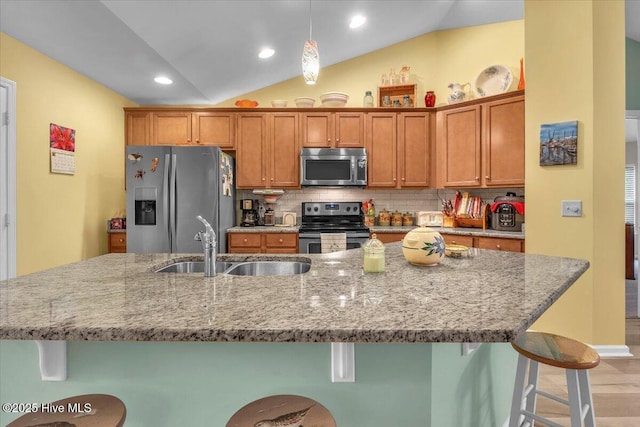 kitchen with sink, a breakfast bar area, tasteful backsplash, vaulted ceiling, and stainless steel appliances