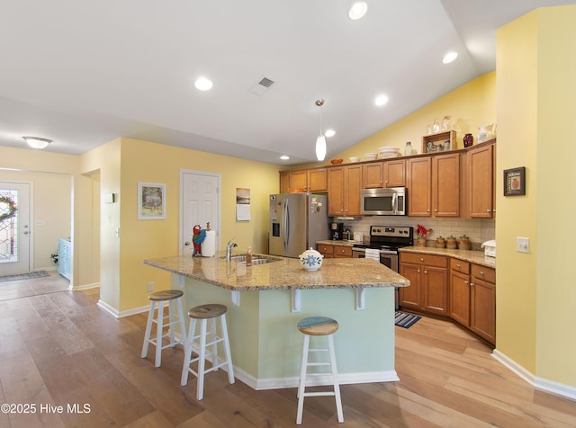 kitchen featuring appliances with stainless steel finishes, tasteful backsplash, sink, a breakfast bar area, and a center island with sink