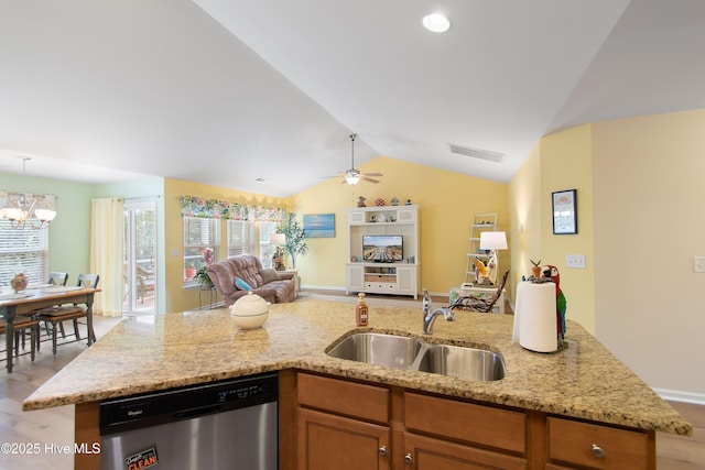 kitchen with sink, light stone counters, vaulted ceiling, a center island with sink, and dishwasher