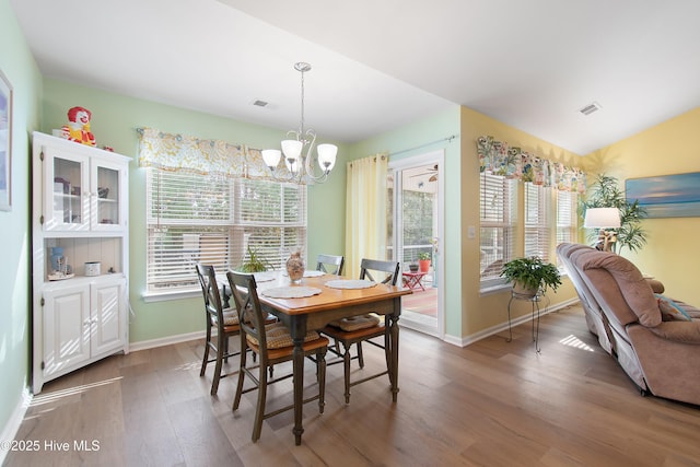 dining room featuring dark wood-type flooring, a wealth of natural light, and a notable chandelier