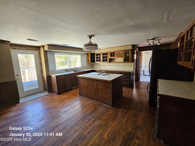 kitchen with black fridge, dark hardwood / wood-style flooring, sink, and a kitchen island