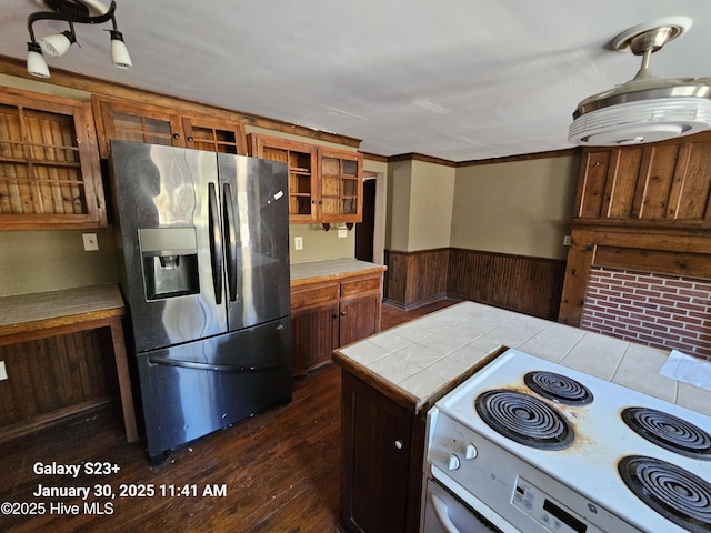 kitchen with white electric range, tile countertops, wood walls, stainless steel fridge, and dark hardwood / wood-style flooring