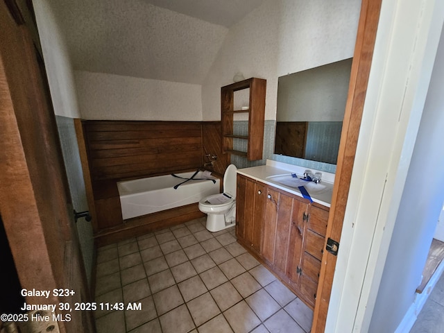 bathroom featuring tile patterned floors, vaulted ceiling, a textured ceiling, vanity, and a bathtub