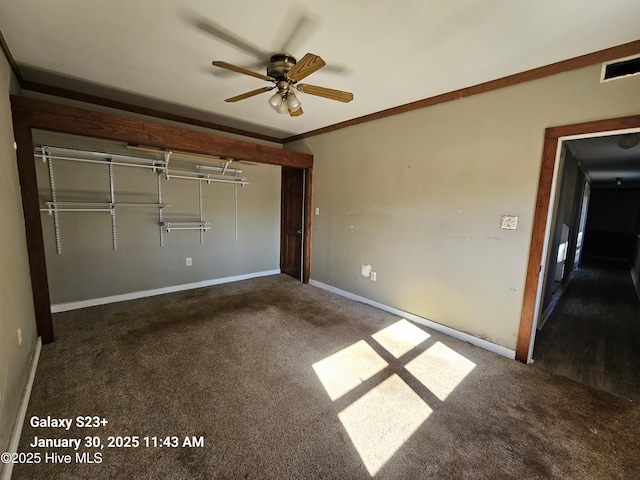 unfurnished bedroom with dark colored carpet, ceiling fan, crown molding, and a closet