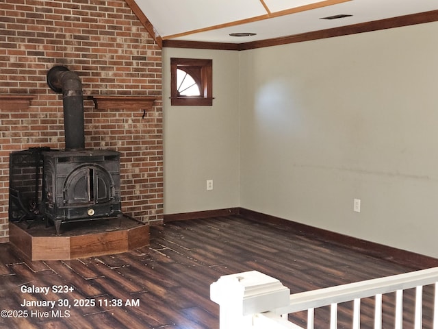 unfurnished living room with crown molding, dark hardwood / wood-style floors, vaulted ceiling, and a wood stove