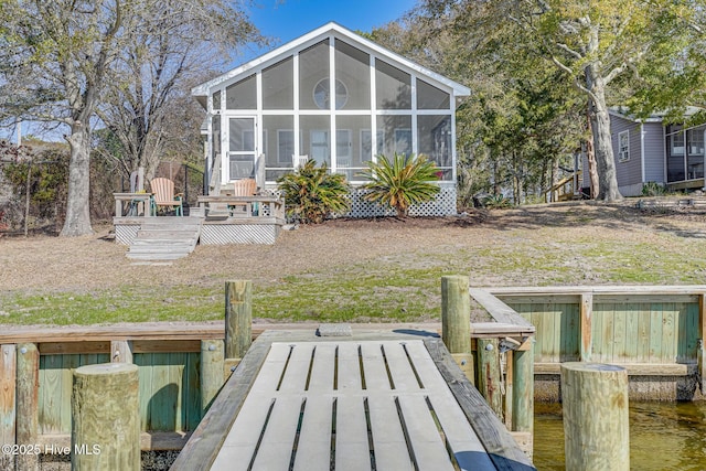 rear view of house featuring a wooden deck, a yard, and a sunroom