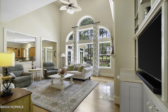 living room featuring a high ceiling, ceiling fan, and light hardwood / wood-style floors