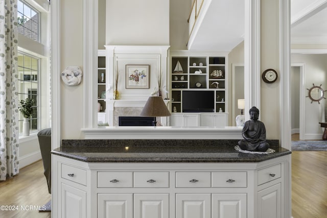 kitchen with dark stone countertops, white cabinets, and light hardwood / wood-style flooring