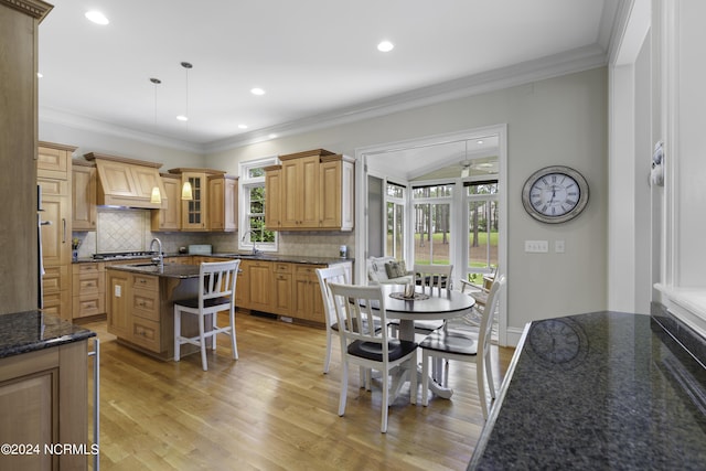 kitchen featuring sink, a breakfast bar, light hardwood / wood-style floors, an island with sink, and decorative light fixtures