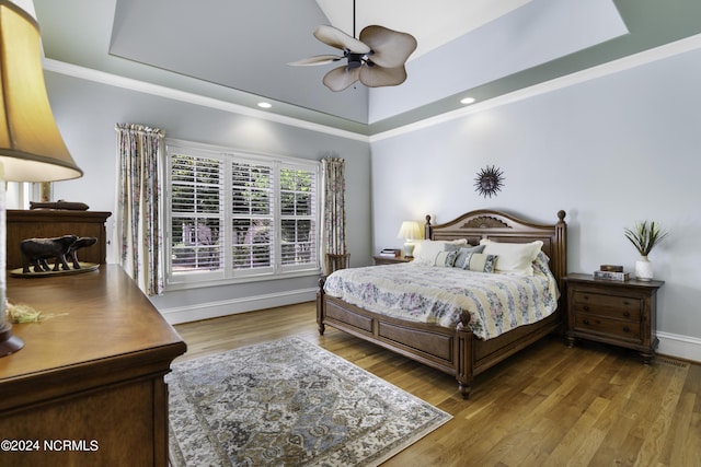 bedroom with a tray ceiling, ornamental molding, and hardwood / wood-style flooring