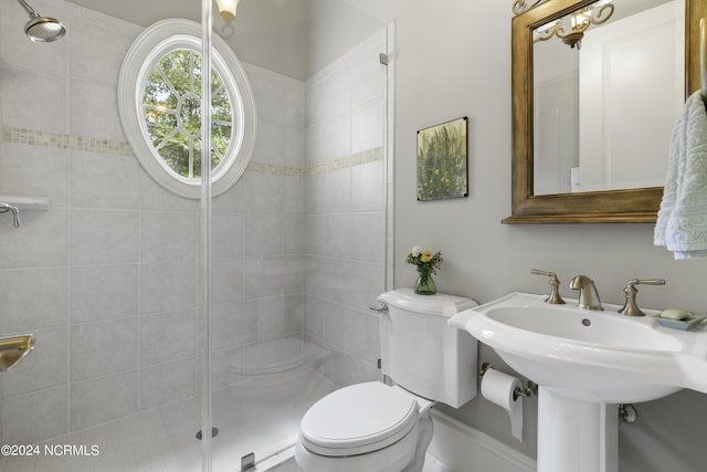 bathroom with sink, a tile shower, and toilet