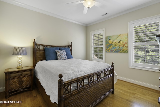 bedroom with multiple windows, hardwood / wood-style floors, and crown molding