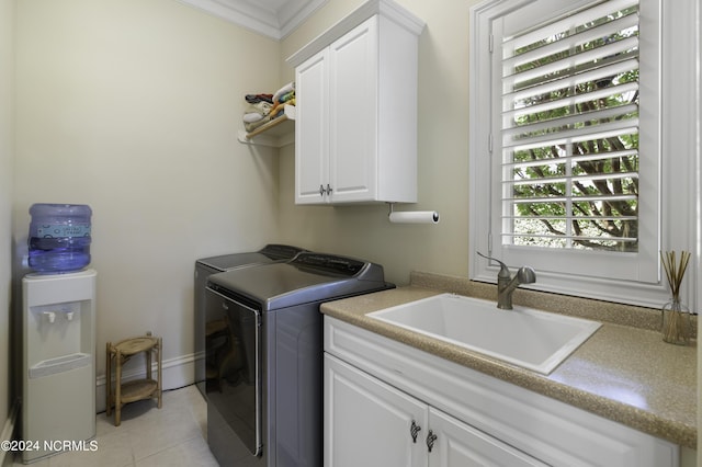 clothes washing area with sink, crown molding, washer and clothes dryer, cabinets, and light tile patterned flooring