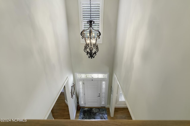 foyer entrance featuring a towering ceiling, a chandelier, and dark hardwood / wood-style flooring