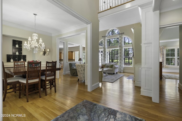 dining space featuring an inviting chandelier, ornamental molding, wood-type flooring, and a high ceiling