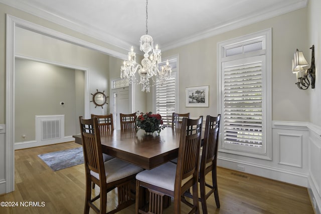 dining room with hardwood / wood-style flooring, ornamental molding, and an inviting chandelier