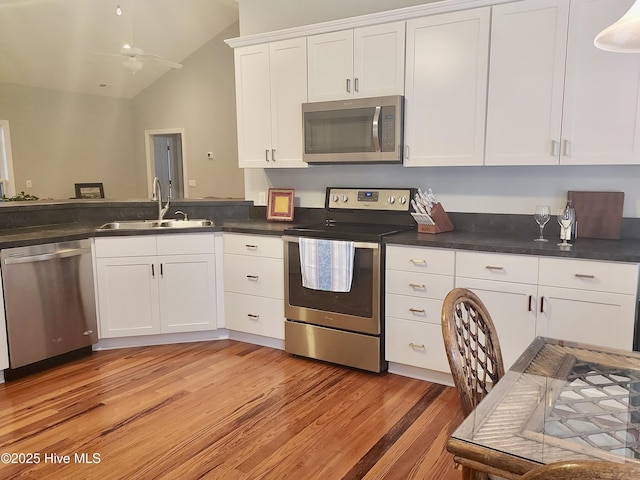 kitchen featuring lofted ceiling, sink, white cabinetry, stainless steel appliances, and light hardwood / wood-style floors