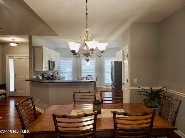 dining area with dark wood-type flooring and a chandelier