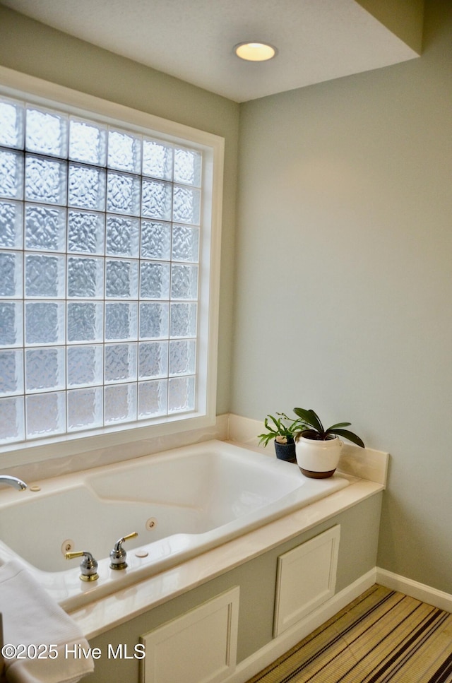 bathroom with a tub to relax in and a healthy amount of sunlight