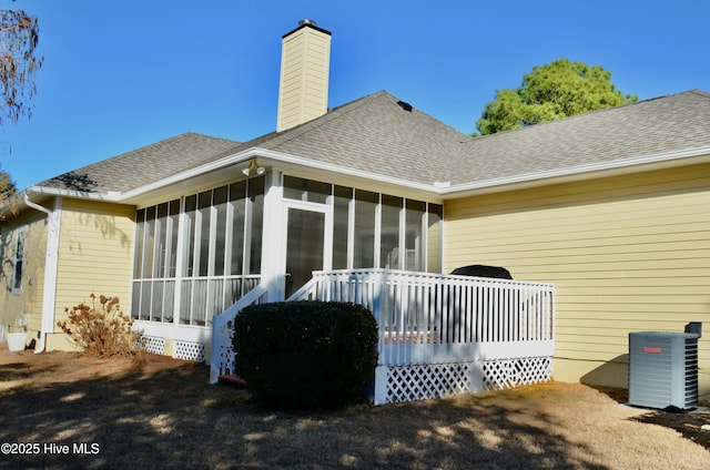 rear view of property with central AC and a sunroom