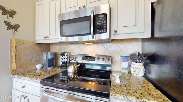 kitchen with white cabinetry, stainless steel appliances, and light stone counters