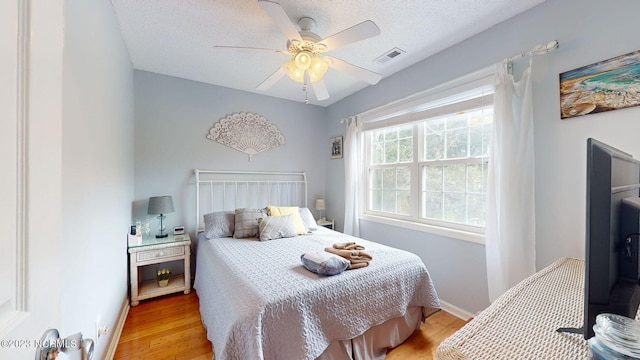 bedroom with ceiling fan, a textured ceiling, and light wood-type flooring