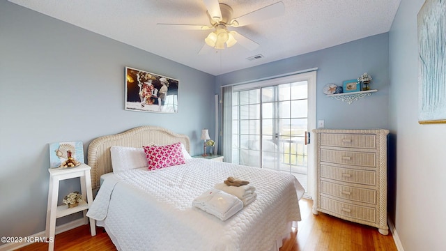 bedroom with ceiling fan, wood-type flooring, and a textured ceiling