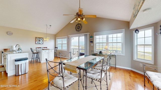 dining space with ceiling fan, lofted ceiling, sink, and light wood-type flooring