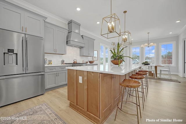 kitchen featuring custom exhaust hood, an inviting chandelier, light countertops, gray cabinetry, and stainless steel appliances