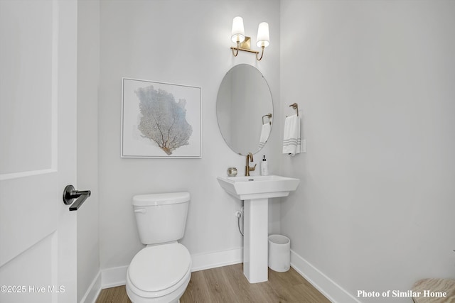 bathroom featuring toilet, wood finished floors, and baseboards