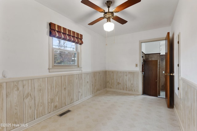 unfurnished room with ceiling fan and wooden walls