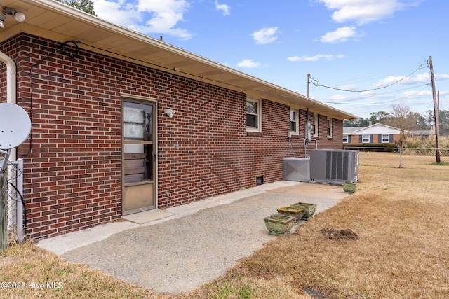 view of side of home featuring a patio, a yard, and central AC unit