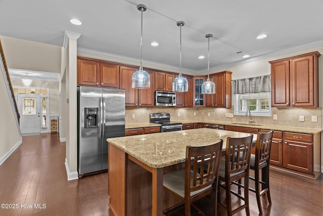 kitchen with pendant lighting, sink, stainless steel appliances, a center island, and a kitchen bar