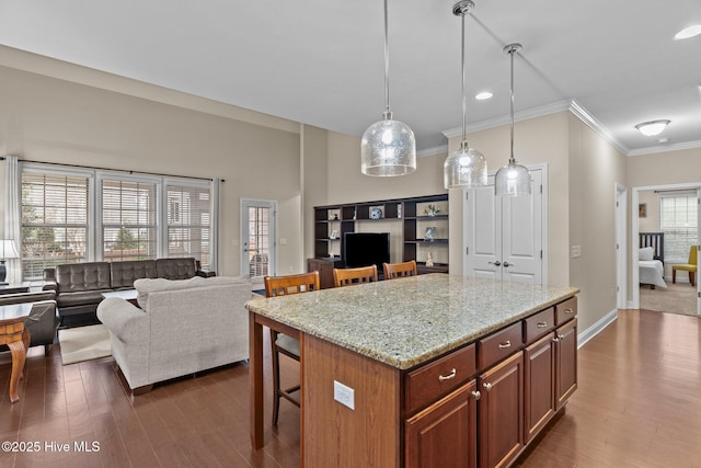 kitchen with a kitchen island, pendant lighting, a breakfast bar area, dark hardwood / wood-style flooring, and light stone counters