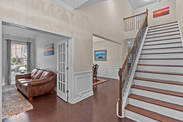 interior space with wood-type flooring, ornamental molding, and a high ceiling