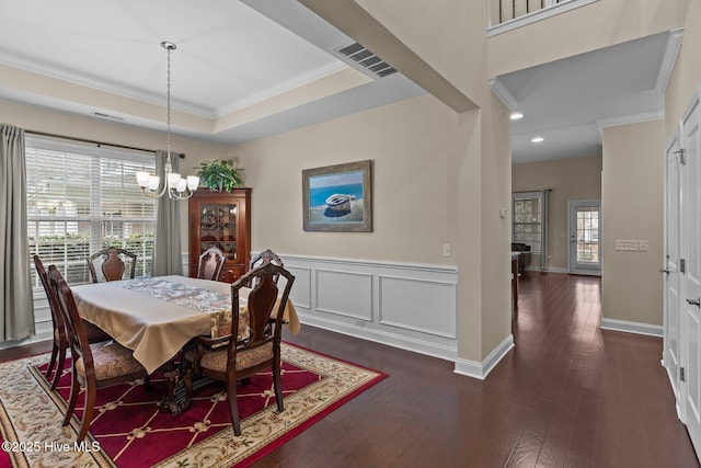 dining area with ornamental molding, dark hardwood / wood-style floors, a chandelier, and a tray ceiling