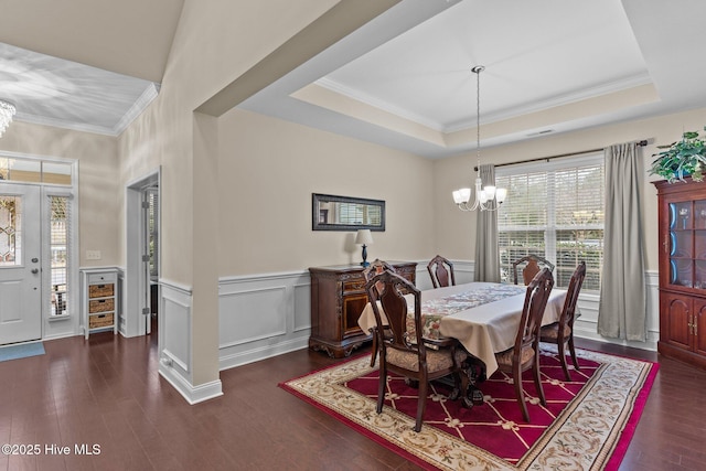 dining space featuring a raised ceiling, dark hardwood / wood-style flooring, ornamental molding, and a chandelier