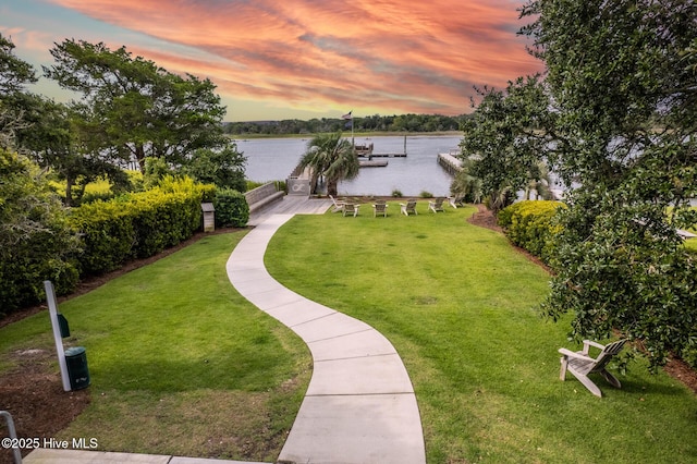 view of home's community featuring a yard, a water view, and a boat dock