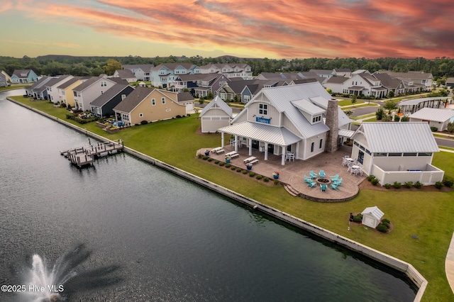 aerial view at dusk with a water view and a residential view