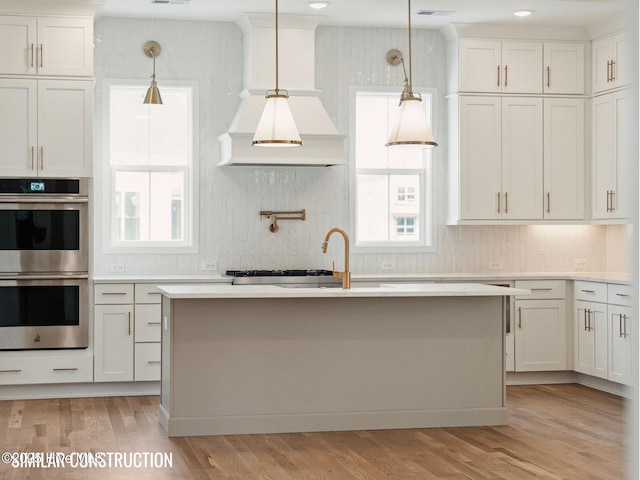 kitchen featuring light countertops, double oven, white cabinets, and pendant lighting