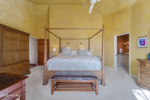 carpeted bedroom with ensuite bathroom and a high ceiling