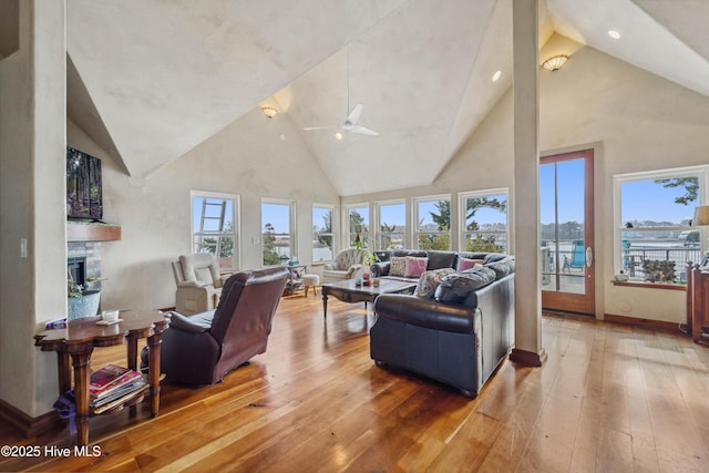 living room featuring a stone fireplace, hardwood / wood-style floors, and high vaulted ceiling